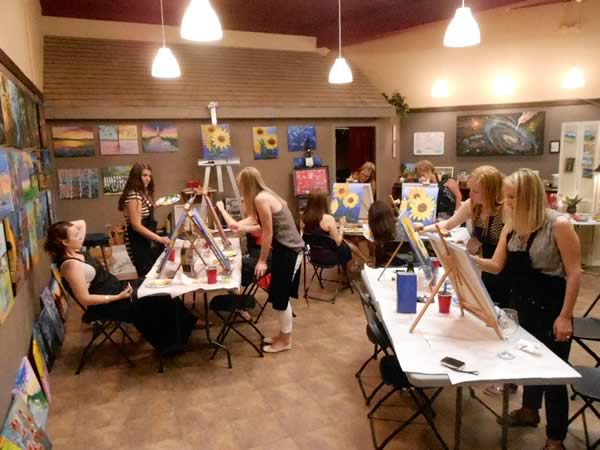 A group of people painting and drinking wine at a stroke of genius.