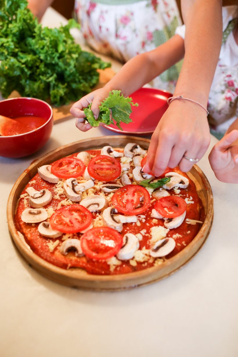 Two people making a pizza together.