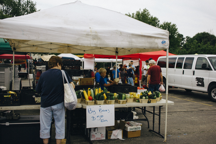 A lady buying corn at the waukesha farmers market.